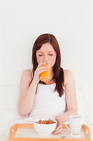 simsearch:400-04881612,k - Attractive red-haired female drinking a glass of orange juice while sitting on her bed Stock Photo - Budget Royalty-Free & Subscription, Code: 400-04881640