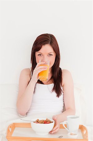 simsearch:400-04881612,k - Good looking red-haired female drinking a glass of orange juice while sitting on her bed Stock Photo - Budget Royalty-Free & Subscription, Code: 400-04881642