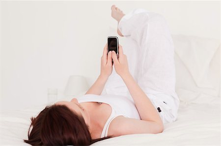 simsearch:6109-06194459,k - Pretty red-haired female relaxing with her mobile while lying on her bed Foto de stock - Super Valor sin royalties y Suscripción, Código: 400-04881665