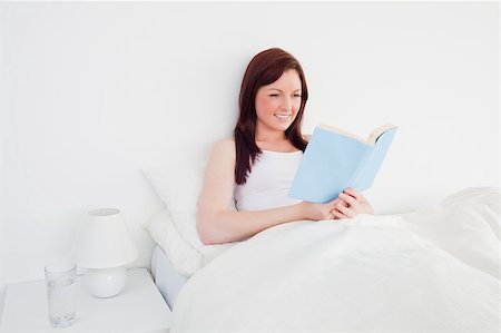 simsearch:400-05894862,k - Beautiful red-haired woman reading a book while sitting on her bed Foto de stock - Super Valor sin royalties y Suscripción, Código: 400-04881680