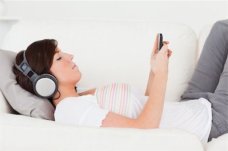 Good looking brunette woman writing a text on her mobile while lying on a sofa in the living room Stock Photo - Budget Royalty-Free & Subscription, Code: 400-04881963
