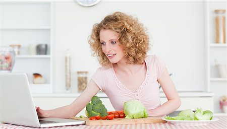 red pepper - Good looking blonde woman relaxing with her laptop while cooking some vegetables in the kitchen in her appartment Foto de stock - Super Valor sin royalties y Suscripción, Código: 400-04883937