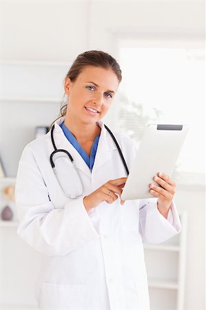 simsearch:400-05192323,k - Doctor having a stethoscope around her neck pointing at a file looking at the camera in the surgery Stock Photo - Budget Royalty-Free & Subscription, Code: 400-04894204