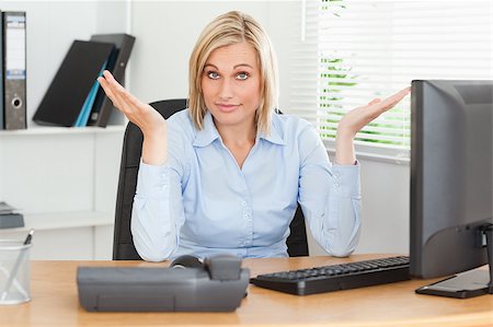 Young blonde woman sitting behind desk not having a clue what to do next in an office Stock Photo - Budget Royalty-Free & Subscription, Code: 400-04894274
