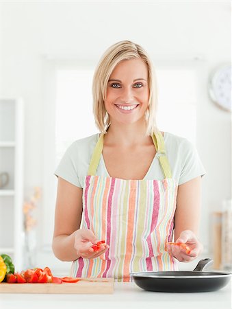 simsearch:400-04139196,k - Young woman frying peppers looking into the camera in the kitchen Foto de stock - Royalty-Free Super Valor e Assinatura, Número: 400-04894338