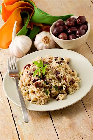tasty risotto with black olives on wooden table with napkin and garlic Stockbilder - Microstock & Abonnement, Bildnummer: 400-04896929
