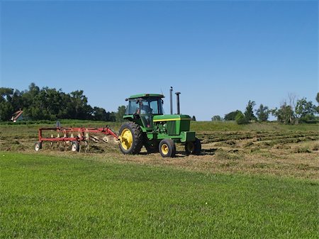 Tractor with hay rake raking rows of hay in a field with a farmhouse in the background. Foto de stock - Super Valor sin royalties y Suscripción, Código: 400-04899039