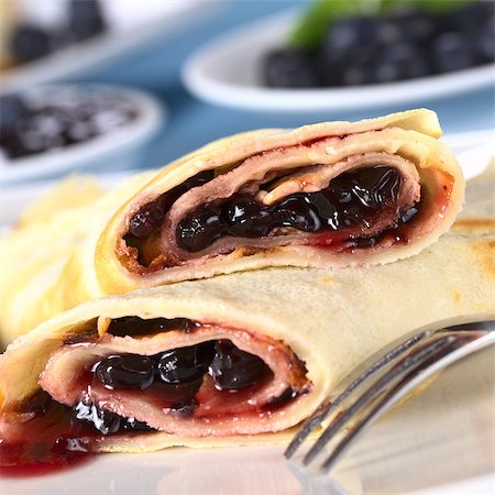 Pancakes filled with blueberry jam with fresh blueberries and jam in the back (Selective Focus, Focus on the front of the upper pancake roll) Stock Photo - Budget Royalty-Free & Subscription, Code: 400-04891090