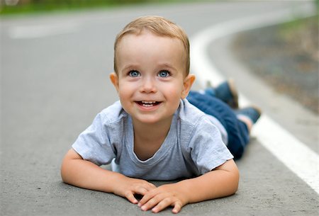 Happy child lying on the pavement Stock Photo - Budget Royalty-Free & Subscription, Code: 400-04893031