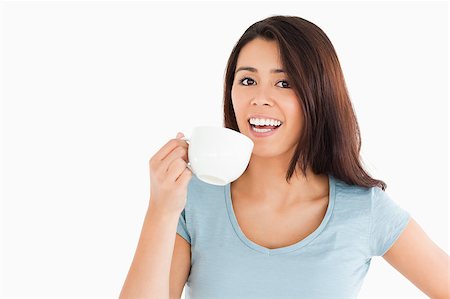Attractive woman enjoying a cup of coffee while standing against a white background Stock Photo - Budget Royalty-Free & Subscription, Code: 400-04893195