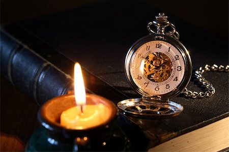 simsearch:400-06772771,k - Vintage pocket watch on book near lighting candle on dark background Photographie de stock - Aubaine LD & Abonnement, Code: 400-04904086