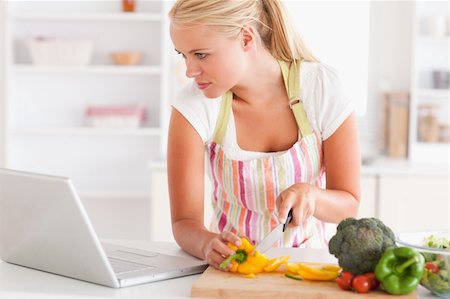 simsearch:400-05748090,k - Close up of a woman using a laptop to cook in her kitchen Foto de stock - Super Valor sin royalties y Suscripción, Código: 400-04904451