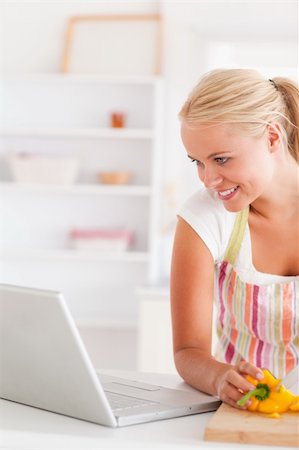 simsearch:400-05748090,k - Close up of a blonde woman using a laptop slicing a pepper in her kitchen Foto de stock - Super Valor sin royalties y Suscripción, Código: 400-04904453