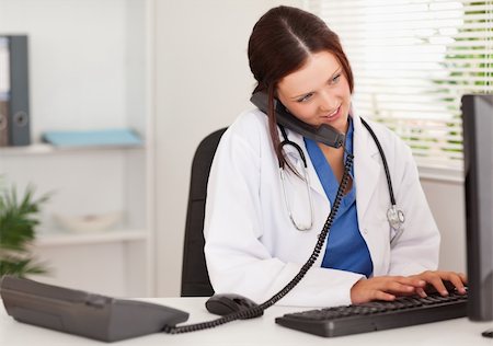 doctor business computer - A female doctor is telephoning whilst typing on her keyboard Stock Photo - Budget Royalty-Free & Subscription, Code: 400-04905043
