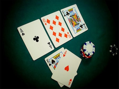 simsearch:400-04314649,k - Angled view of a TEXAS HOLD EM hand. This stage of the game is known as THE FLOP, three cards dealt face up on the table (ACE KING TEN). The player has thrown his two HOLE CARDS face up on the table (KING ACE) because he is ALL IN with a pretty good hand of a pair of Aces and a pair of Kings. Foto de stock - Royalty-Free Super Valor e Assinatura, Número: 400-04905834
