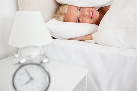 simsearch:6109-06194408,k - Tired woman hidding her head in a pillow while the alarmclock is ringing in her bedroom Stockbilder - Microstock & Abonnement, Bildnummer: 400-04906017