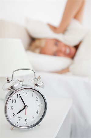 simsearch:6109-06194890,k - Portrait of a woman hidding her head in a pillow while the alarmclock is ringing in her bedroom Stockbilder - Microstock & Abonnement, Bildnummer: 400-04906018