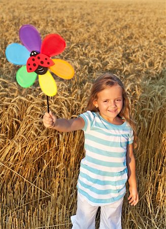 Little girl in whet field at harvest time playing with windmill toy Stock Photo - Budget Royalty-Free & Subscription, Code: 400-04907054