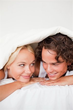 simsearch:400-04903640,k - Portrait of a couple under a duvet with a knowing smile in a bed Photographie de stock - Aubaine LD & Abonnement, Code: 400-04903665