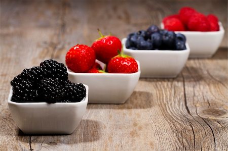 photos of blueberries for kitchen - some bowls filled with wild berries on wooden background blackberries in front Foto de stock - Super Valor sin royalties y Suscripción, Código: 400-04916896