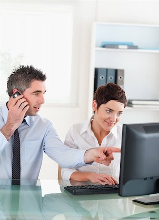 Portrait of a man showing something to his coworker on a computer in an office Stock Photo - Budget Royalty-Free & Subscription, Code: 400-04917856