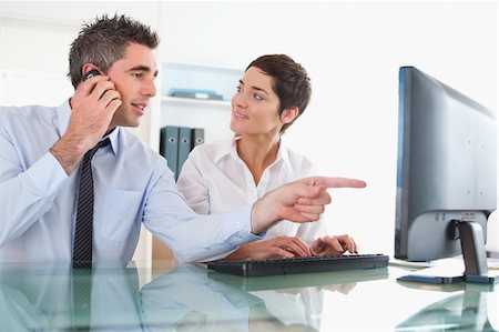 Close up of a man showing something to his coworker on a computer against a white background Stock Photo - Budget Royalty-Free & Subscription, Code: 400-04917886