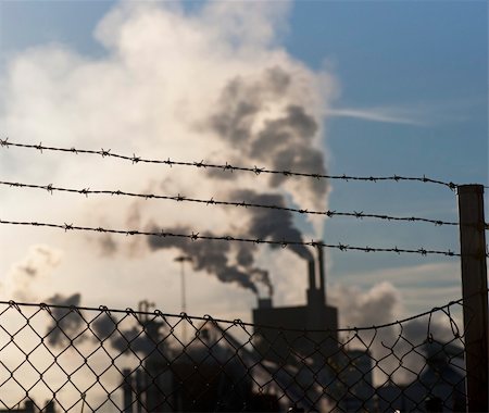 environmental issues petrochemicals - Barbed wire and chainlink fence iwth smoking factory in background Stock Photo - Budget Royalty-Free & Subscription, Code: 400-04917934