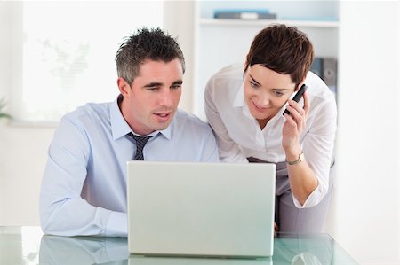 Coworkers working with a laptop and a cellphone in an office Stock Photo - Budget Royalty-Free & Subscription, Code: 400-04918301