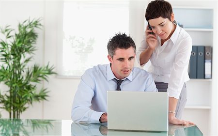 Colleagues working with a laptop and a cellphone in an office Stock Photo - Budget Royalty-Free & Subscription, Code: 400-04918312