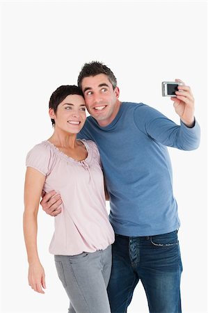 simsearch:400-04151970,k - Portrait of a couple taking a picture of themselves against a white background Fotografie stock - Microstock e Abbonamento, Codice: 400-04918339