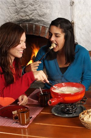 Photo of two beautiful females dipping bread into the melted cheese in a fondue pot. Focus is on girl on the right. Stock Photo - Budget Royalty-Free & Subscription, Code: 400-04919993