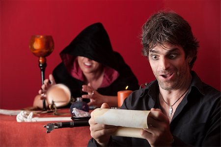 simsearch:400-05347613,k - Man with scroll smiles with hooded fortuneteller in background Stock Photo - Budget Royalty-Free & Subscription, Code: 400-04910579