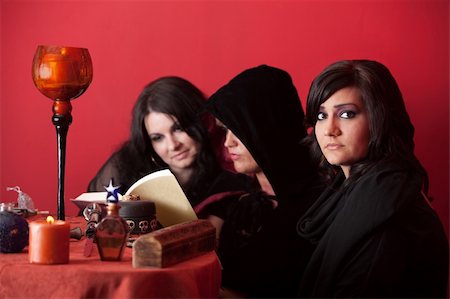 simsearch:400-05347613,k - Witch wearing black veil reads spells with partners over maroon background Stock Photo - Budget Royalty-Free & Subscription, Code: 400-04910585