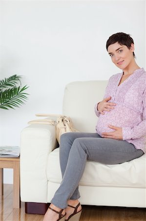 Pretty pregnant woman sitting on a sofa touching her belly in a waiting room Stock Photo - Budget Royalty-Free & Subscription, Code: 400-04910870
