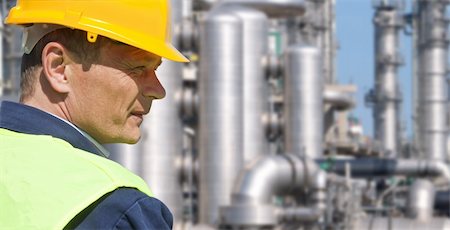 Close up of an engineer wearing a safety vest, blue coveralls, and a hard hat in front of a petrochemical plant Photographie de stock - Aubaine LD & Abonnement, Code: 400-04913176