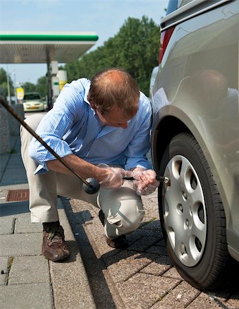 Man, inflating a tire and checking for the proper air pressure in the wheels of his car Photographie de stock - Aubaine LD & Abonnement, Code: 400-04913184