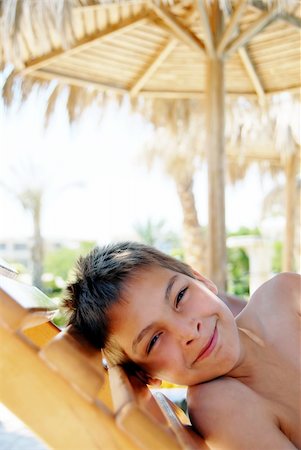 smiling teenage boy portrait lying under sunshade on beach Stock Photo - Budget Royalty-Free & Subscription, Code: 400-04924010