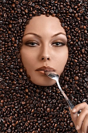 close up portrait of a pretty girl immersed in coffee beans with a spoon in her mouth Stock Photo - Budget Royalty-Free & Subscription, Code: 400-04925560