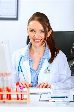 simsearch:400-04925813,k - Smiling medical doctor woman sitting at office table and working on computer Stock Photo - Budget Royalty-Free & Subscription, Code: 400-04925799