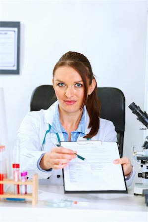 simsearch:400-04925813,k - Medical doctor woman sitting at office table with document and pen for signing Stock Photo - Budget Royalty-Free & Subscription, Code: 400-04925814