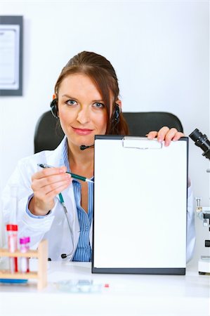 simsearch:400-04925813,k - Medical doctor woman sitting at office table showing blank clipboard and pen for signing Stock Photo - Budget Royalty-Free & Subscription, Code: 400-04925819