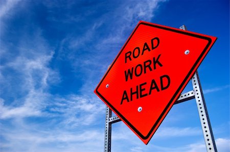 Image of a bright orange road work ahead sign against a blue sky with light clouds Stock Photo - Budget Royalty-Free & Subscription, Code: 400-04925891
