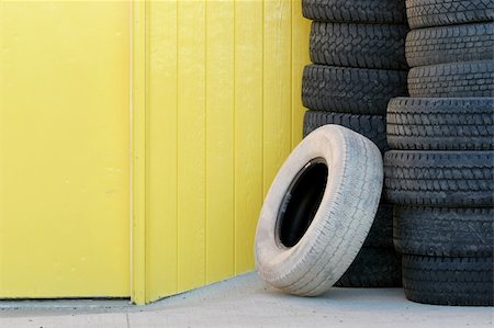 pile tires - stack of tires / tyres against yellow wall and door, one odd white tire leaning against the others. Stock Photo - Budget Royalty-Free & Subscription, Code: 400-04934773