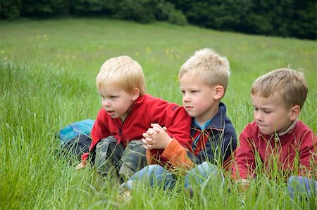 simsearch:400-06768635,k - Three boyfriends sitting in the grass looking at something Foto de stock - Royalty-Free Super Valor e Assinatura, Número: 400-04935603