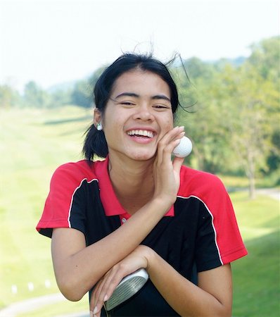Young, female golf player smiling, holding golf club and ball, with fairway in the background. Stock Photo - Budget Royalty-Free & Subscription, Code: 400-04937038