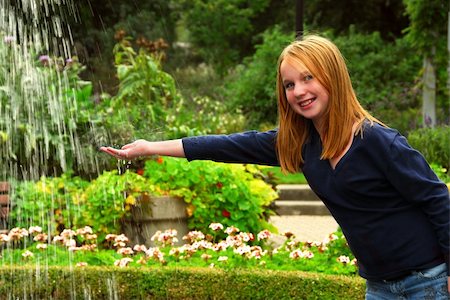 Young girl holding her hand under falling water in a garden Stock Photo - Budget Royalty-Free & Subscription, Code: 400-04938616