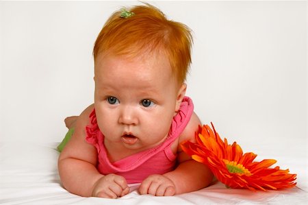 simsearch:400-08557256,k - A baby girl lying on her stomach next to a orange flower Foto de stock - Super Valor sin royalties y Suscripción, Código: 400-04939036