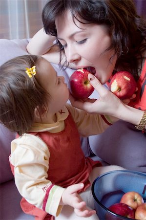 baby girl and her mother with apples feeding each other, sitting on a sofa Stock Photo - Budget Royalty-Free & Subscription, Code: 400-04939846
