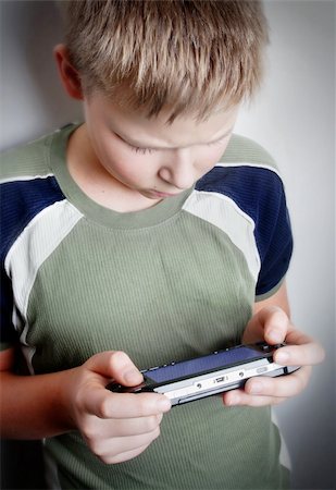 Boys hand playing portable video game Stock Photo - Budget Royalty-Free & Subscription, Code: 400-04933474