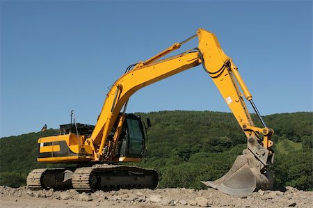 Yellow digger standing idle on a building construction site with rural countryside and a blue sky to the rear. Stock Photo - Budget Royalty-Free & Subscription, Code: 400-04944938